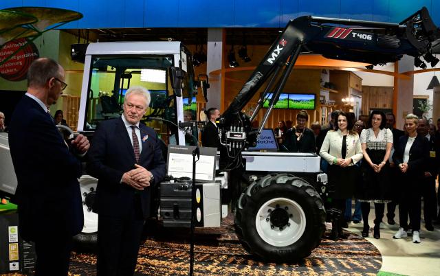German Minister for Agriculture Alois Rainer (2nd L) delivers a statement next to German Chancellor Friedrich Merz (L) and in front of an Onox1 electric tractor at the end of his tour at the "Gruene Woche" (Green Week) International Agriculture Fair in Berlin on January 20, 2026. The 100th edition of the Green Week, one of the world's leading events in the food, agriculture and horticulture sectors, will be running from January 16 to 25, 2026, and some 1600 exhibitors from over 50 countries are presenting their products and services. (Photo by John MACDOUGALL / AFP)