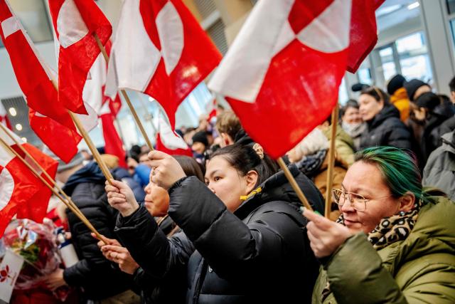 People hold up Greenlandic flags as they gather to welcome Greenland's Foreign Minister after she landed at the airport in Greenland's capital Nuuk on January 20, 2026. (Photo by Mads Claus Rasmussen / Ritzau Scanpix / AFP) / Denmark OUT