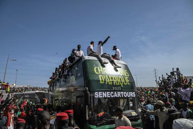 Senegal's Football Team players greet a crowd of supporters while riding on an open bus past supporters during a trophy parade in the streets of Dakar on January 20, 2026 as they celebrate Senegal winning the Africa Cup of Nations (CAN) that was hosted in Morocco. Senegal won the Africa Cup of Nations in Rabat on January 18, 2026, Pape Gueye's extra-time winner sinking hosts Morocco 1-0 after a chaotic final that saw the eventual champions storm off the pitch late in the game. (Photo by NICOLAS REMENE / AFP)