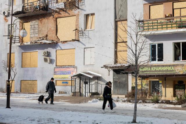 Local residents walk by a damaged residential building in Kramatorsk, eastern Ukraine on January 20, 2026, amid the Russian invasion of Ukraine. (Photo by Tetiana DZHAFAROVA / AFP)