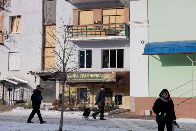 Local residents walk by a damaged residential building in Kramatorsk, eastern Ukraine on January 20, 2026, amid the Russian invasion of Ukraine. (Photo by Tetiana DZHAFAROVA / AFP)