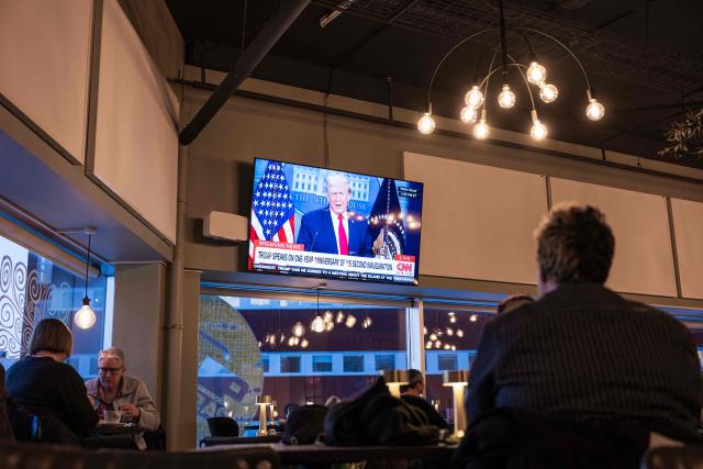 People sit inside a cafe in Nuuk, Greenland, on January 20, 2026 as a TV broadcasts US President Donald Trump. (Photo by Jonathan NACKSTRAND / AFP)