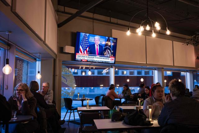 People sit inside a cafe in Nuuk, Greenland, on January 20, 2026 as a TV broadcasts US President Donald Trump. (Photo by Jonathan NACKSTRAND / AFP)