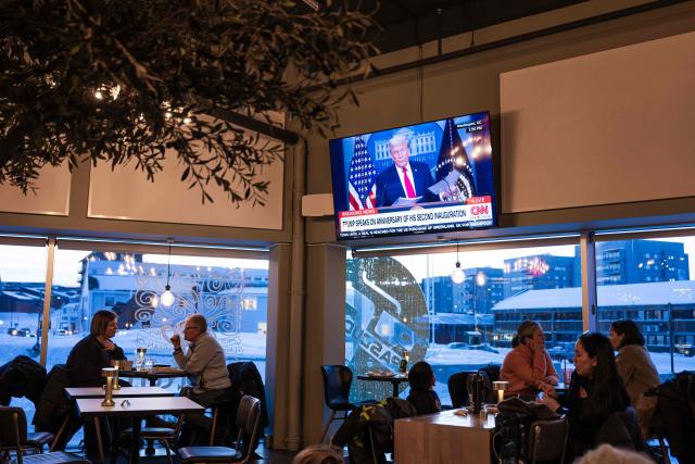 People sit inside a cafe in Nuuk, Greenland, on January 20, 2026 as a TV broadcasts US President Donald Trump. (Photo by Jonathan NACKSTRAND / AFP)