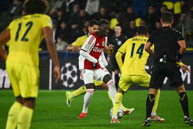 Ajax's Belgian defender #24 Jorthy Mokio runs with the ball past Villarreal's Spanish midfielder #14 Santi Comesana during the UEFA Champions League league phase day 7 football match between Villarreal CF and Ajax at La Ceramica Stadium in Vila-real on January 20, 2026. (Photo by JOSE JORDAN / AFP)
