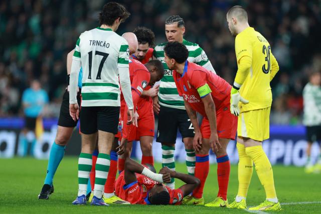 Players check on Paris Saint-Germain's Ecuadoran defender #51 Willian Pacho (BOTTOM) after resulting injured during the UEFA Champions League league phase day 7 football match between Sporting CP and Paris Saint Germain at Jose Alvalade stadium in Lisbon on January 20, 2026. (Photo by PATRICIA DE MELO MOREIRA / AFP)