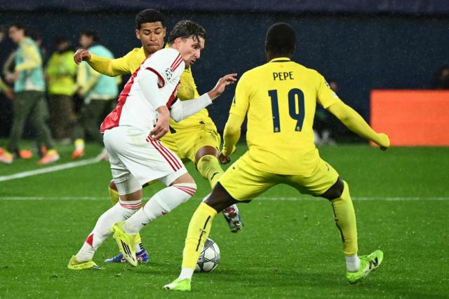 Ajax's Belgian forward #11 Mika Godts (L) controls the ball past Villarreal's Uruguayan defender #15 Santiago Mourino (behind) and Ivorian forward #19 Nicolas Pepe (R) during the UEFA Champions League league phase day 7 football match between Villarreal CF and Ajax at La Ceramica Stadium in Vila-real on January 20, 2026. (Photo by JOSE JORDAN / AFP)