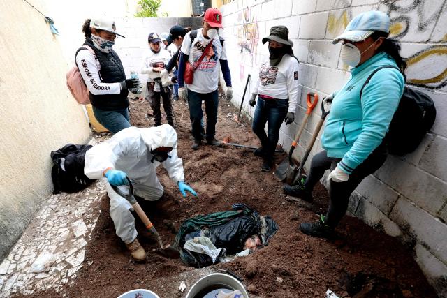EDITORS NOTE: Graphic content / Members of the "Guerreros Buscadores" (Searching Warriors) collective dig up a body from a clandestine grave during a search at a drug house in Tlajomulco de Zuniga, Jalisco state, Mexico on January 20, 2026. The Mexican collective "Guerreros Buscadores" went to an area near a drug house in Tlajomulco de Zuniga after receiving an anonymous tip that several bodies had recently been buried there, while the National Guard arrested one suspect. (Photo by ULISES RUIZ / AFP)