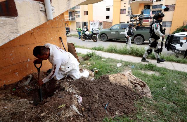A member of the "Guerreros Buscadores" (Searching Warriors) collective digs in the ground during a search for bodies near a drug house in Tlajomulco de Zuniga, Jalisco state, Mexico on January 20, 2026. The Mexican collective "Guerreros Buscadores" went to an area near a drug house in Tlajomulco de Zuniga after receiving an anonymous tip that several bodies had recently been buried there, while the National Guard arrested one suspect. (Photo by Ulises RUIZ / AFP)