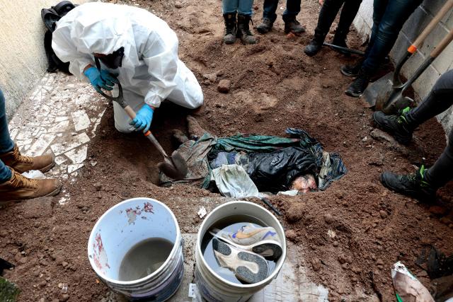 EDITORS NOTE: Graphic content / A member of the "Guerreros Buscadores" (Searching Warriors) collective digs up a body from a clandestine grave during a search at a drug house in Tlajomulco de Zuniga, Jalisco state, Mexico on January 20, 2026. The Mexican collective "Guerreros Buscadores" went to an area near a drug house in Tlajomulco de Zuniga after receiving an anonymous tip that several bodies had recently been buried there, while the National Guard arrested one suspect. (Photo by ULISES RUIZ / AFP)