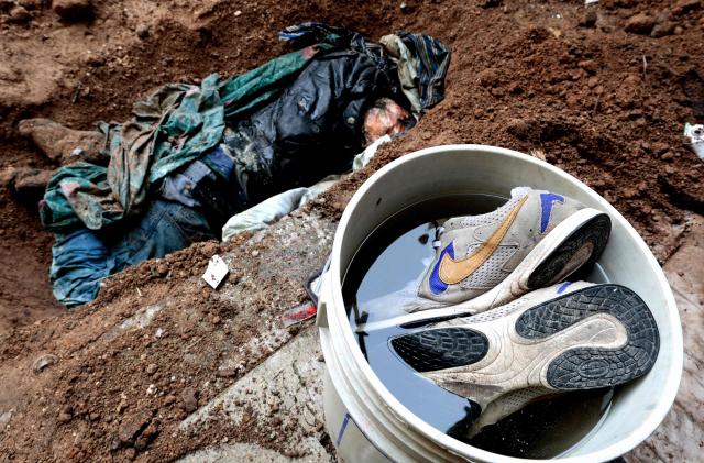 EDITORS NOTE: Graphic content / A body unearthed by the "Guerreros Buscadores" (Searching Warriors) collective is seen next to a pair of sneakers submerged in a bucket during a search at a drug house in Tlajomulco de Zuniga, Jalisco state, Mexico on January 20, 2026. The Mexican collective "Guerreros Buscadores" went to an area near a drug house in Tlajomulco de Zuniga after receiving an anonymous tip that several bodies had recently been buried there, while the National Guard arrested one suspect. (Photo by ULISES RUIZ / AFP)