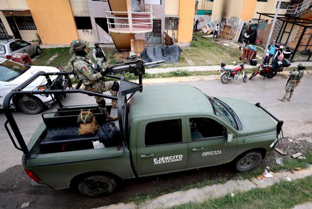 Mexican soldiers guard the area where the "Guerreros Buscadores" (Searching Warriors) collective search bodies near a drug house in Tlajomulco de Zuniga, Jalisco state, Mexico on January 20, 2026. The Mexican collective "Guerreros Buscadores" went to an area near a drug house in Tlajomulco de Zuniga after receiving an anonymous tip that several bodies had recently been buried there, while the National Guard arrested one suspect. (Photo by ULISES RUIZ / AFP)