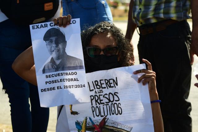 A woman shows signs during a demonstration to demand the freedom of Venezuelan political prisoners in front of Tocuyito prison in Tocuyito, near Valencia, Venezuela on January 20, 2026. Relatives of political prisoners reported on January 20, 2026, that some 200 people are in a state of "forced disappearance" in Venezuela and demanded proof of life from the prosecutor's office, amid a slow process of releases from prison under pressure from United States. (Photo by Jacinto OLIVEROS / AFP)