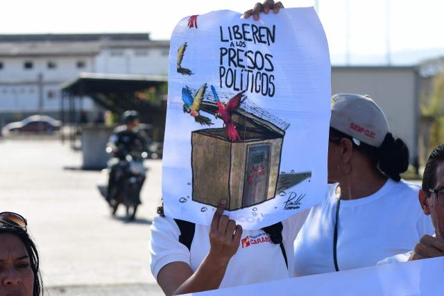 A person shows a sign during a demonstration to demand the freedom of Venezuelan political prisoners in front of Tocuyito prision in Tocuyito, near Valencia, Venezuela on January 20, 2026. Relatives of political prisoners reported on January 20, 2026, that some 200 people are in a state of "forced disappearance" in Venezuela and demanded proof of life from the prosecutor's office, amid a slow process of releases from prison under pressure from United States. (Photo by Jacinto OLIVEROS / AFP)