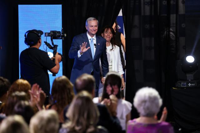 Chile's President-elect Jose Antonio Kast, waves as he arrives with his wife, María Pia Adriasola to the presentation of his cabinet at the office of the president-elect, commonly nicknamed 'La Moneda Chica,' in Las Condes, Santiago, on January 20, 2026. Chile's right-wing president-elect Jose Antonio Kast on january 20 named two ex-lawyers of former dictator Augusto Pinochet to lead the ministries of defense and human rights when he takes office in March. (Photo by Alvaro NARANJO / AFP)