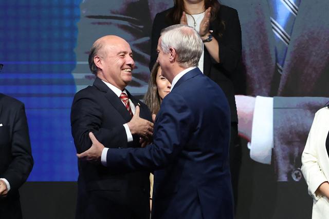 Chile's President-elect Jose Antonio Kast (R) greets Jorge Quiroz as new Minister of Finance during the presentation of his cabinet at the office of the president-elect, commonly nicknamed 'La Moneda Chica,' in Las Condes, Santiago, on January 20, 2026. Chile's right-wing president-elect Jose Antonio Kast on January 20 named two ex-lawyers of former dictator Augusto Pinochet to lead the ministries of defense and human rights when he takes office in March. (Photo by Alvaro NARANJO / AFP)