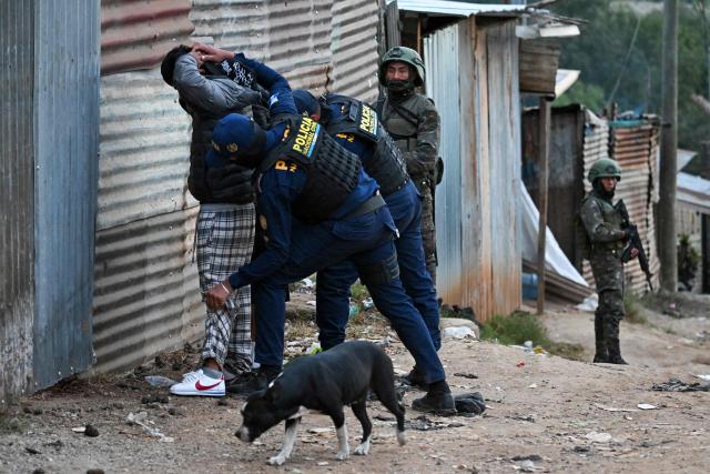 Guatemalan police officers search two men on a street of the Nueva Jerusalen neighborhood during the state of emergency declared by the government in Guatemala City on January 20, 2026. Guatemalan soldiers began patrolling gang-controlled neighborhoods in the capital on Tuesday, after attacks that left ten police officers dead and prompted the government to declare a state of siege, according to official sources and an AFP journalist. (Photo by JOHAN ORDONEZ / AFP)