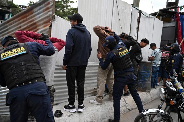 Guatemalan police officers search a group of young men on a street of the Nueva Jerusalen neighborhood during the state of emergency declared by the government in Guatemala City on January 20, 2026. Guatemalan soldiers began patrolling gang-controlled neighborhoods in the capital on Tuesday, after attacks that left ten police officers dead and prompted the government to declare a state of siege, according to official sources and an AFP journalist. (Photo by JOHAN ORDONEZ / AFP)