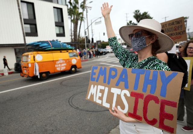 A demonstrator holds a sign during the Free America Walkout to protest against Immigration and Customs Enforcement (ICE) and US President Donald Trump's policies in the Venice Beach neighborhood of Los Angeles, California on January 20, 2026. (Photo by Patrick T. Fallon / AFP)