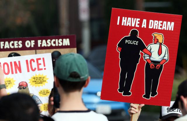 Demonstrators hold signs during the Free America Walkout to protest against Immigration and Customs Enforcement (ICE) and US President Donald Trump's policies in the Venice Beach neighborhood of Los Angeles, California on January 20, 2026. (Photo by Patrick T. Fallon / AFP)