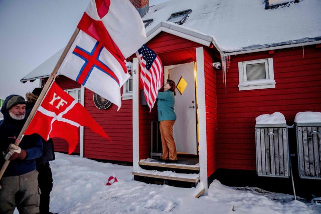 A protester holds flag outside the US consulate in Nuuk, Greenland, on January 20, 2026. Greenland is at the centre of the geopolitical spotlight after US President Donald Trump's bid to seize the island. Trump has said that the United States needs Greenland, which would dramatically increase the US land mass, because of a threat of Russia or China seizing the island as climate change opens up Arctic water routes. (Photo by Mads Claus Rasmussen / Ritzau Scanpix / AFP) / Denmark OUT