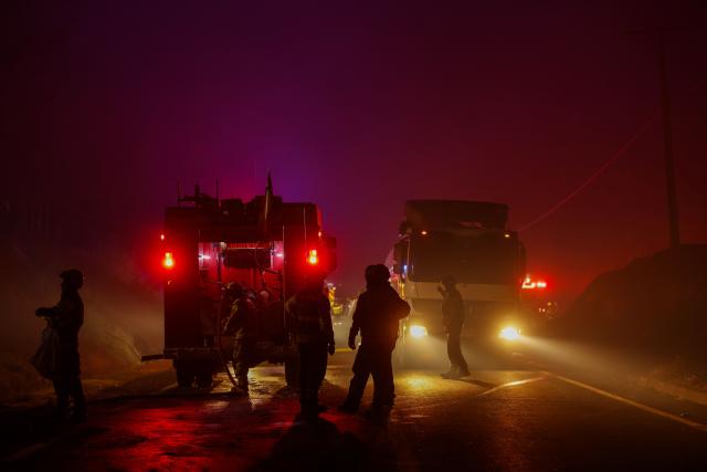 Firefighters work on a wildfire in the town of Florida near the city of Concepción, Chile, on January 20, 2026. Residents of southern Chile, ravaged by four days of deadly wildfires, pleaded for help on January 20 from communities reduced to rubble, as smoke lingered and firefighters braced for the return of hot weather. (Photo by Raul BRAVO / AFP)