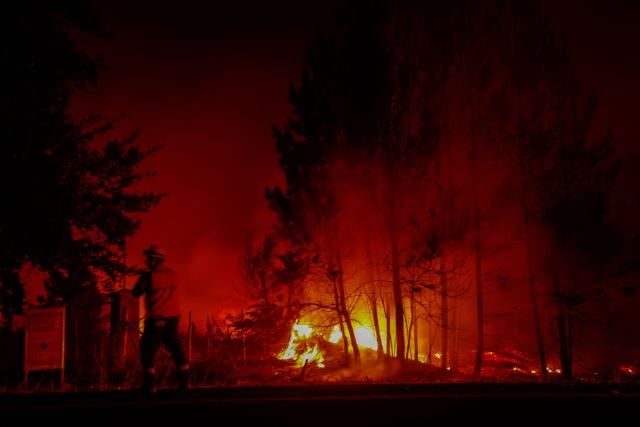 Flames and burning vegetation are seen during a wildfire in the town of Florida near the city of Concepción, Chile, on January 20, 2026. Residents of southern Chile, ravaged by four days of deadly wildfires, pleaded for help on January 20 from communities reduced to rubble, as smoke lingered and firefighters braced for the return of hot weather. (Photo by Raul BRAVO / AFP)