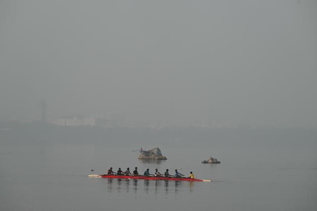 Rowers practice in Hussain Sagar Lake amid smog in Hyderabad on January 21, 2026. (Photo by Noah SEELAM / AFP)