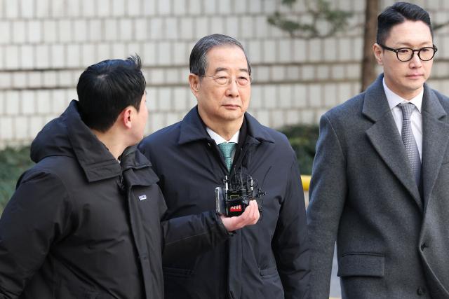 Former South Korean prime minister Han Duck-soo (C) arrives at the Seoul Central District Court for his first sentencing trial in the insurrection case in Seoul on January 21, 2026> (Photo by Chung Sung-Jun / POOL / AFP)