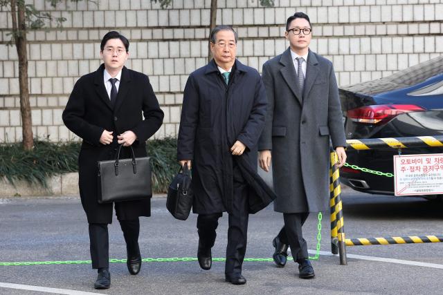 Former South Korean prime minister Han Duck-soo (C) arrives at the Seoul Central District Court for his first sentencing trial in the insurrection case in Seoul on January 21, 2026> (Photo by Chung Sung-Jun / POOL / AFP)