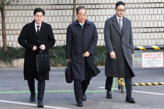 Former South Korean prime minister Han Duck-soo (C) arrives at the Seoul Central District Court for his first sentencing trial in the insurrection case in Seoul on January 21, 2026> (Photo by Chung Sung-Jun / POOL / AFP)