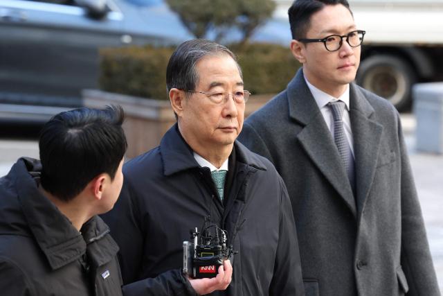 Former South Korean prime minister Han Duck-soo (C) arrives at the Seoul Central District Court for his first sentencing trial in the insurrection case in Seoul on January 21, 2026> (Photo by Chung Sung-Jun / POOL / AFP)