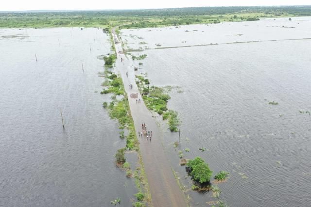 This aerial view shows residents wading through floodwater to cross a road near Maputo on January 20, 2026. At least 114 people have died since the rainy season began in early October 2025, including 51 since Christmas Eve, when downpours intensified and sent torrents of river water crashing through several villages.
The United Nations says the surging waters have spiralled into a rapidly escalating emergency. (Photo by Emidio JOZINE / AFP)