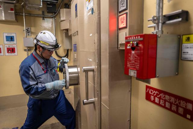 (FILES) This picture taken on August 6, 2024 shows a Tokyo Electric Power Co. (Tepco) employee opening a watertight door inside the unit 7 reactor building at the Kashiwazaki-Kariwa nuclear power station in Kashiwazaki, in Japan's Niigata prefecture. The world's biggest nuclear power plant is set to restart on January 21, 2026, for the first time since the 2011 Fukushima disaster, its Japanese operator said, despite persistent safety concerns among residents. (Photo by Yuichi YAMAZAKI / AFP)