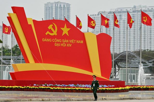 A military officer walks past a billboard for the 14th National Congress of the Communist Party of Vietnam at the National Convention Centre in Hanoi on January 21, 2026. (Photo by Nhac NGUYEN / AFP)