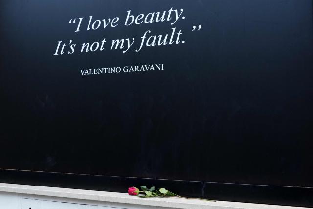A red rose is laid by Valentino's shop window covered with a black poster reading "I love beauty, It is not my fault - Valentino Garavani", in Rome on January 21, 2026. Valentino’s lying-in-state open today in Rome ahead of the funeral on January 23, 2026. (Photo by Stefano Costantino / AFP)