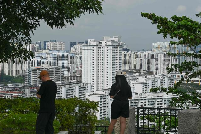 People stand on the hillside looking at highrise housing apartments in Singapore on January 21, 2026. (Photo by Roslan RAHMAN / AFP)