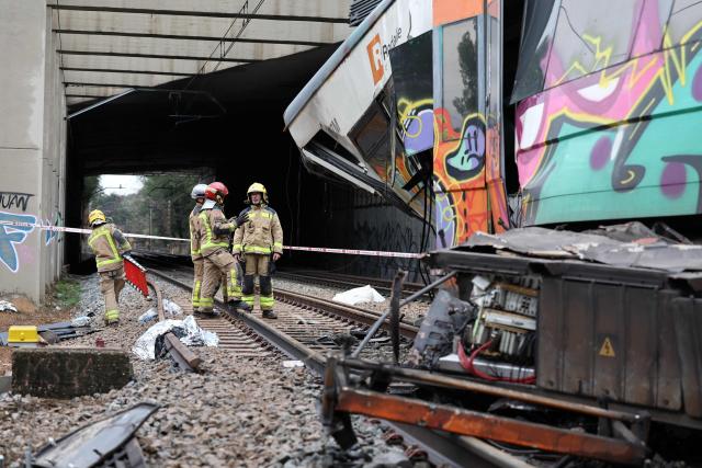 Firefighters stand next to the locomotive as they work at the site where at least one person died and five were seriously injured when a regional service train collided with a collapsed wall  between Sant Sadurni d'Anoia and Gelida, near Barcelona, on January 21, 2026. The latest incident is likely to raise more questions about Spanish rail safety after the collision of two high-speed trains in the southern region of Andalusia on Sunday killed 42 people and injured more than 120.  (Photo by Josep LAGO / AFP)