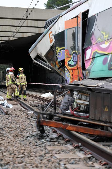 Firefighters stand next to the locomotive as they work at the site where at least one person died and five were seriously injured when a regional service train collided with a collapsed wall  between Sant Sadurni d'Anoia and Gelida, near Barcelona, on January 21, 2026. The latest incident is likely to raise more questions about Spanish rail safety after the collision of two high-speed trains in the southern region of Andalusia on Sunday killed 42 people and injured more than 120.  (Photo by Josep LAGO / AFP)