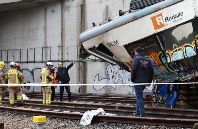 Firefighters and investigators stand next to the locomotive as they work at the site where at least one person died and five were seriously injured when a regional service train collided with a collapsed wall  between Sant Sadurni d'Anoia and Gelida, near Barcelona, on January 21, 2026. The latest incident is likely to raise more questions about Spanish rail safety after the collision of two high-speed trains in the southern region of Andalusia on Sunday killed 42 people and injured more than 120.  (Photo by Josep LAGO / AFP)