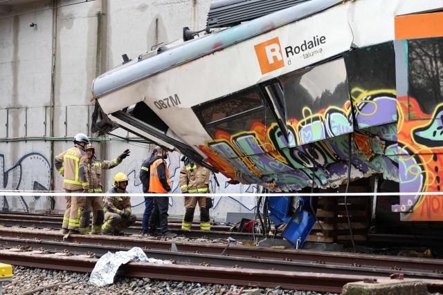 Firefighters and investigators stand next to the locomotive as they work at the site where at least one person died and five were seriously injured when a regional service train collided with a collapsed wall  between Sant Sadurni d'Anoia and Gelida, near Barcelona, on January 21, 2026. The latest incident is likely to raise more questions about Spanish rail safety after the collision of two high-speed trains in the southern region of Andalusia on Sunday killed 42 people and injured more than 120.  (Photo by Josep LAGO / AFP)