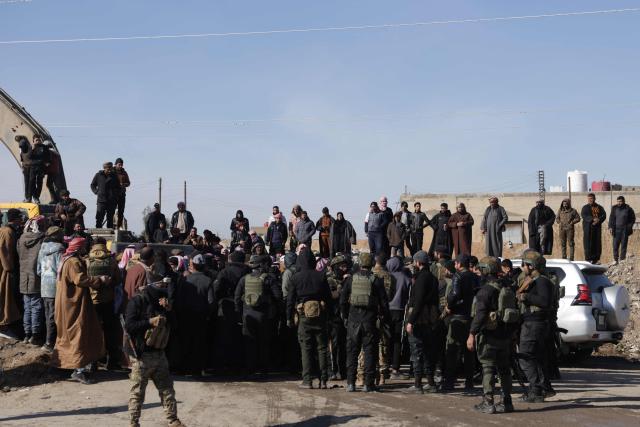 Syrian security forces stand guard as family members of detainees in Al-Aqtan prison on the outskirts of the northeastern Syrian city of Raqa gather outside the facility as they try to have news about their detained relatives on January 21, 2026. The government announced a new ceasefire with the Kurds after taking swathes of north and east Syria that had long been under the control of Kurdish-led Syrian Democratic Forces (SDF). The United States, which has long headed an international coalition and backed the Kurds against IS, said the purpose of its alliance with the SDF had largely ended years after they defeated the jihadists. Now, the United States was backing Syria's new Islamist authorities who are seeking to extend their control across the country after years of civil war. (Photo by Bakr ALkasem / AFP)