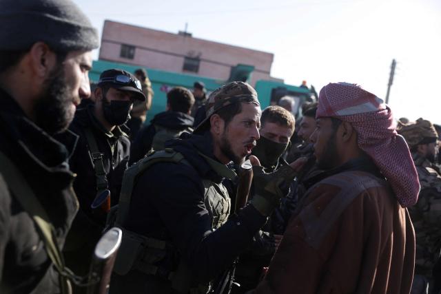 A member of the Syrian security forces speaks to a man as family members of detainees in Al-Aqtan prison on the outskirts of the northeastern Syrian city of Raqa gather outside the facility as they try to have news about their detained relatives on January 21, 2026. The government announced a new ceasefire with the Kurds after taking swathes of north and east Syria that had long been under the control of Kurdish-led Syrian Democratic Forces (SDF). The United States, which has long headed an international coalition and backed the Kurds against IS, said the purpose of its alliance with the SDF had largely ended years after they defeated the jihadists. Now, the United States was backing Syria's new Islamist authorities who are seeking to extend their control across the country after years of civil war. (Photo by Bakr ALkasem / AFP)