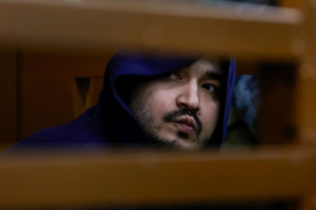 Akhmadzhon Kurbonov, charged with the December 2024 killing of the Russian army's chemical weapons division head, Lieutenant General Igor Kirillov, looks out from inside a glass cage during the verdict announcement at a military court in Moscow on January 21, 2026. (Photo by TATYANA MAKEYEVA / AFP)