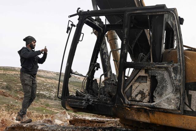 A Palestinian man inspects a burnt bulldozer following a reported attack by Israeli settlers at a stone works processing plant in Orif village near the Israeli-occupied northern West Bank city of Nablus on January 21, 2026. Israel has occupied the West Bank since 1967, and violence there has soared since the Gaza war erupted in October 2023 following Hamas's attack on Israel. Some 3,200 Palestinians from dozens of Bedouin and herding communities have been forced from their homes by settler violence and movement restrictions since October 2023, the UN's humanitarian agency OCHA reported in October. All Israeli settlements in the West Bank are considered illegal by the international community. (Photo by JAAFAR ASHTIYEH / AFP)
