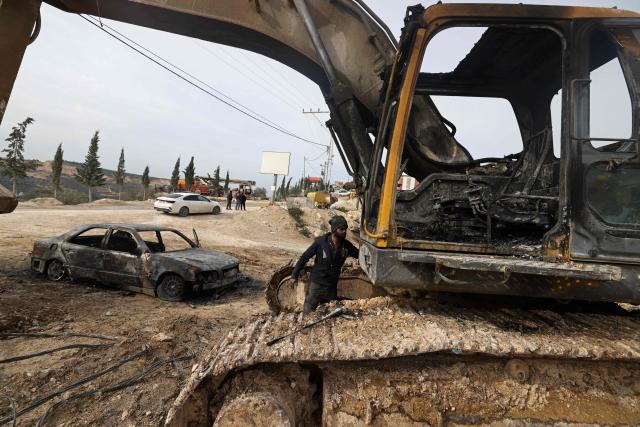 A Palestinian man inspects a burnt car and a bulldozer following a reported attack by Israeli settlers at a stone works processing plant in Orif village near the Israeli-occupied northern West Bank city of Nablus on January 21, 2026. Israel has occupied the West Bank since 1967, and violence there has soared since the Gaza war erupted in October 2023 following Hamas's attack on Israel. Some 3,200 Palestinians from dozens of Bedouin and herding communities have been forced from their homes by settler violence and movement restrictions since October 2023, the UN's humanitarian agency OCHA reported in October. All Israeli settlements in the West Bank are considered illegal by the international community. (Photo by JAAFAR ASHTIYEH / AFP)