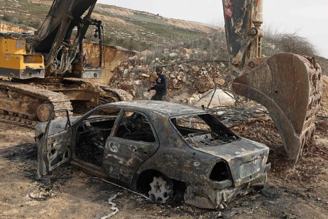 TOPSHOT - A Palestinian man inspects a burnt car and a bulldozer following a reported attack by Israeli settlers at a stone works processing plant in Orif village near the Israeli-occupied northern West Bank city of Nablus on January 21, 2026. Israel has occupied the West Bank since 1967, and violence there has soared since the Gaza war erupted in October 2023 following Hamas's attack on Israel. Some 3,200 Palestinians from dozens of Bedouin and herding communities have been forced from their homes by settler violence and movement restrictions since October 2023, the UN's humanitarian agency OCHA reported in October. All Israeli settlements in the West Bank are considered illegal by the international community. (Photo by JAAFAR ASHTIYEH / AFP)