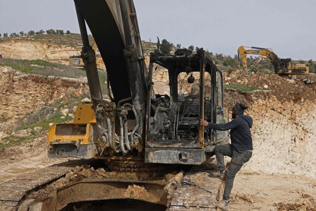 A Palestinian man inspects a burnt bulldozer following a reported attack by Israeli settlers at a stone works processing plant in Orif village near the Israeli-occupied northern West Bank city of Nablus on January 21, 2026. Israel has occupied the West Bank since 1967, and violence there has soared since the Gaza war erupted in October 2023 following Hamas's attack on Israel. Some 3,200 Palestinians from dozens of Bedouin and herding communities have been forced from their homes by settler violence and movement restrictions since October 2023, the UN's humanitarian agency OCHA reported in October. All Israeli settlements in the West Bank are considered illegal by the international community. (Photo by JAAFAR ASHTIYEH / AFP)