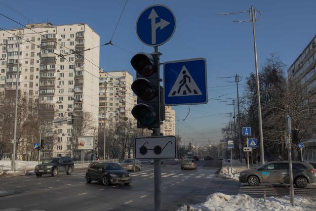 Cars drive on the road with unlit traffic signals due to a power outage in Kyiv, following Russian missile and drone attacks on Ukrainian energy infrastructure on January 21, 2026 amid the Russian invasion in Ukraine. (Photo by Roman PILIPEY / AFP)