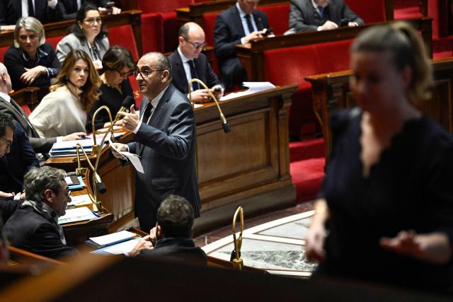 President of La France Insoumise - Nouveau Front Populaire parliamentary group Mathilde Panot (R) walks past France's Interior Minister Laurent Nunez (C) addressing MPs during a session of questions to the government at The National Assembly, France's lower house parliament, in Paris on January 21, 2026. (Photo by JULIEN DE ROSA / AFP)